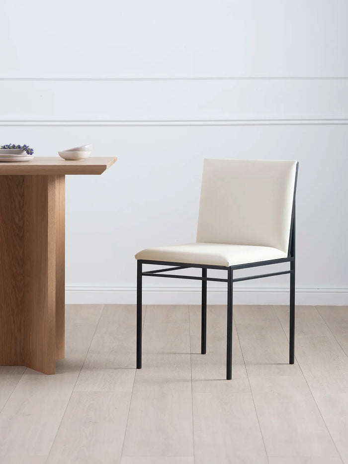 Dining chair Bella features a black frame and ivory leather cushion, perfect for a modern dining space.