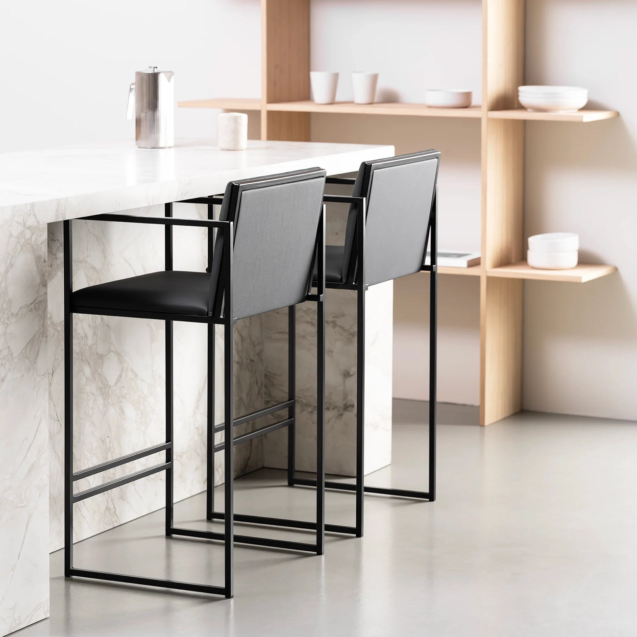 Bruno bar stools in black leather at a modern kitchen bar with marble countertop, showcasing minimalist design and elegance.