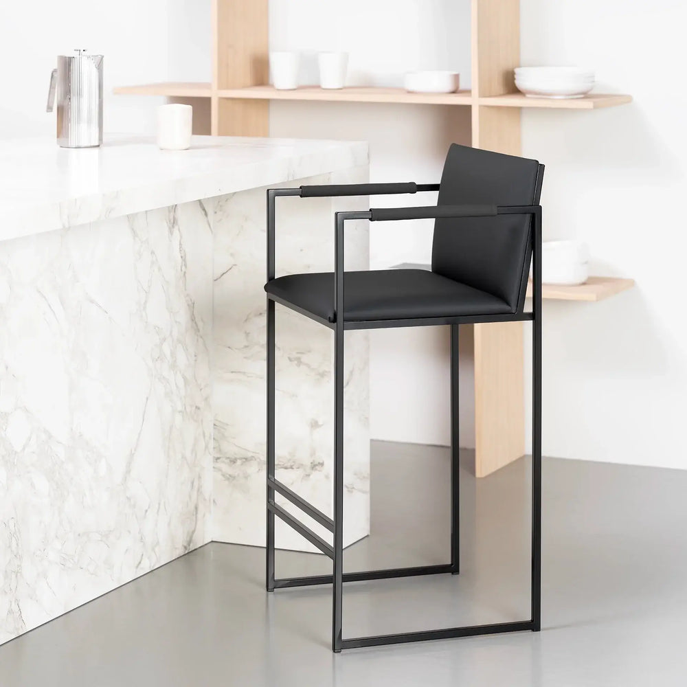 Bar Stool Bruno – Black – Jade Black Leather with sleek design and black armrests in modern kitchen setting.