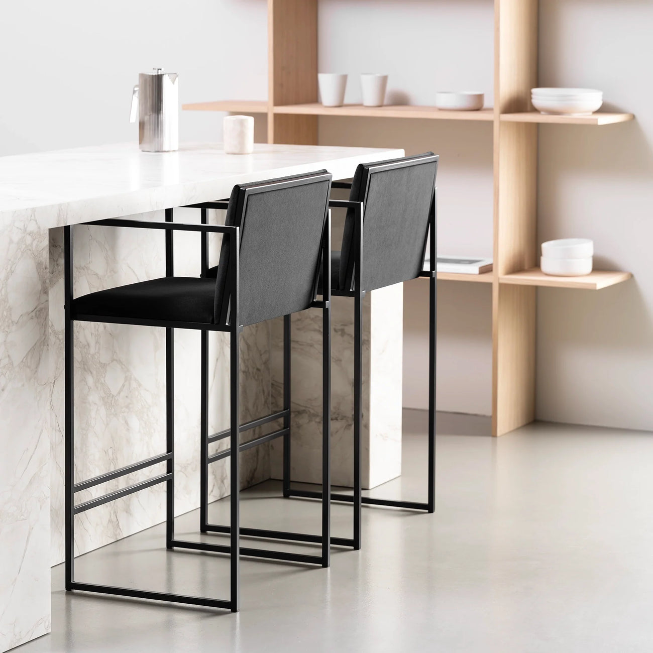Bruno bar stools in black velvet at a modern kitchen island, showcasing Scandinavian design and sleek armrests.