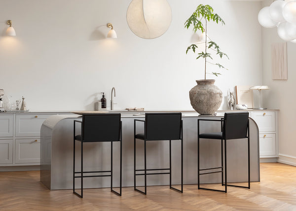 Bar Stool Bruno with armrests on a black steel frame in an interior setting