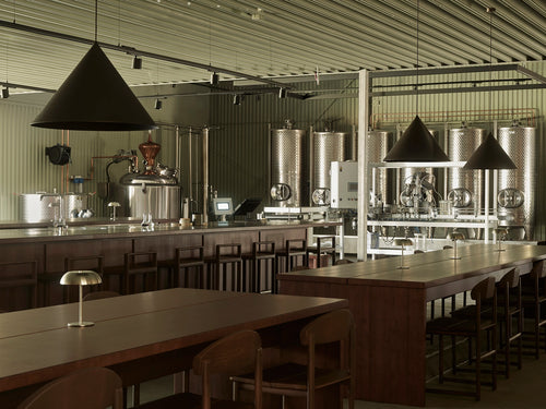 Dark wood by Crea bar stools arranged around the bar and communal tables at Norrbottens Destilleri’s grand opening.
