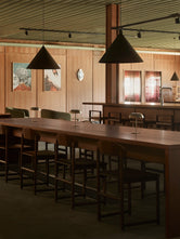 Dark wood Karin chairs and Ebba bar stools from by Crea arranged around the tables and bar at Norrbottens Destilleri.