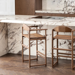 Carl bar stools in dark oak at a modern kitchen island with marble countertops.