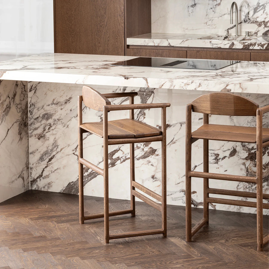 Carl bar stools in dark oak at a modern kitchen island with marble countertops.