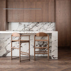 Carl wooden bar stools in dark oak by a modern kitchen island with marble countertop.