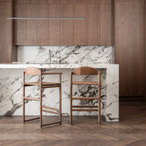 Oak Bar Stool at a modern kitchen island with dark oak wood cabinets and marble countertop.