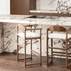 Two dark oak bar stools with ivory bouclé seats in a modern kitchen with marble countertops.