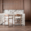Stylish dark oak bar stools with ivory bouclé seats in a modern kitchen with marble countertop.