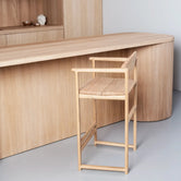 Oak Bar Stool Carl in a minimalist kitchen setting with a wooden frame and seat.