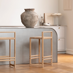 Ebba bar stools handcrafted in solid natural oak, styled against a curved light grey kitchen island with warm wooden flooring and minimalist decor.