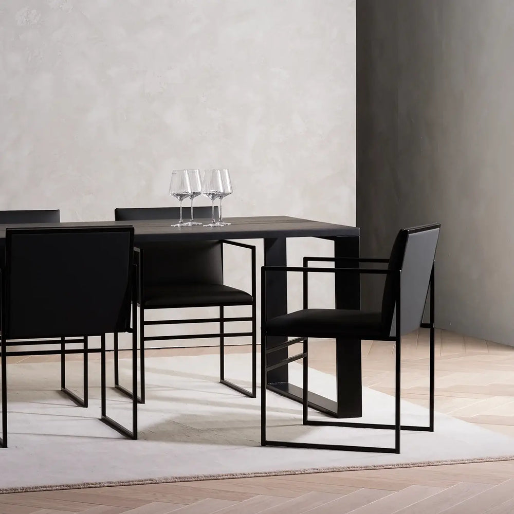 Dining Table Diana in black stained oak seen from the corner, with black Sella dining chairs and a Sella armchair