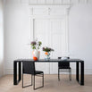 Diana dining table in black oak with modern chairs and floral centerpiece in a stylish dining space.