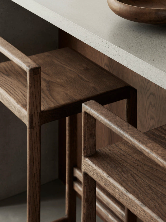 Close-up of handcrafted solid oak bar stools highlighting wood texture and joinery in a minimalist Scandinavian kitchen.