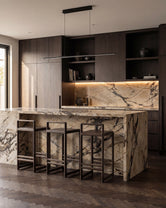 Ebba bar stools in dark oak placed at a dramatic marble kitchen island with bold veining, styled in a sophisticated Scandinavian kitchen with dark wood cabinetry and warm integrated lighting.