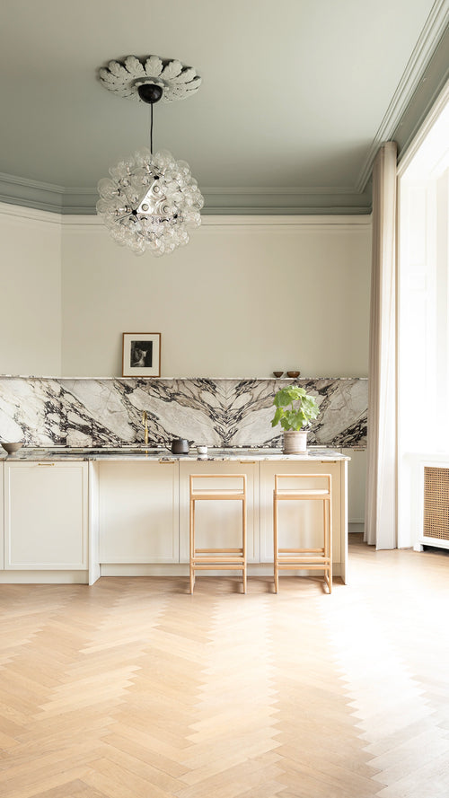Ebba bar stools in a Danish design kitchen inside a Copenhagen apartment featuring marble backsplash, herringbone oak flooring, and soft Scandinavian daylight.
