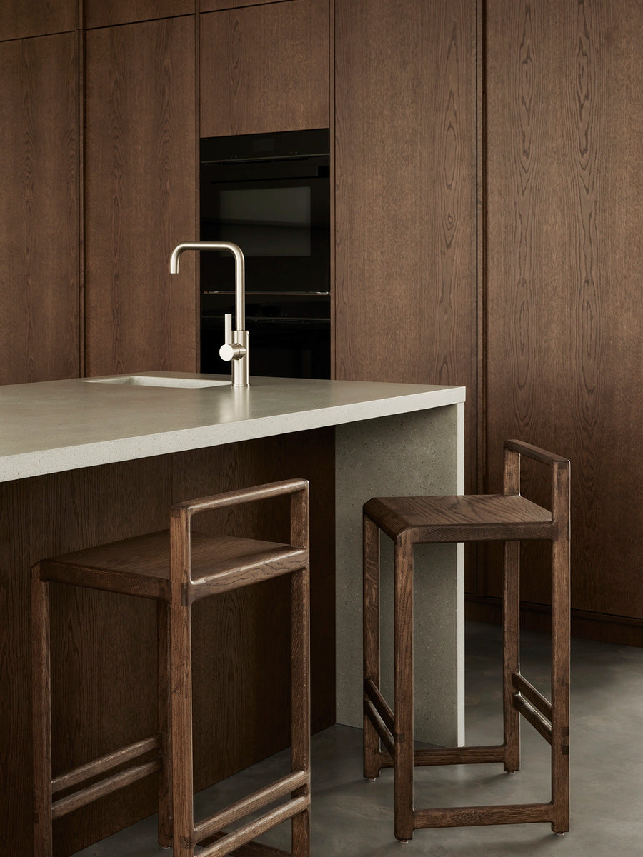 Ebba bar stools in dark-stained solid oak placed by a minimalist kitchen island in a Stockholm archipelago villa.