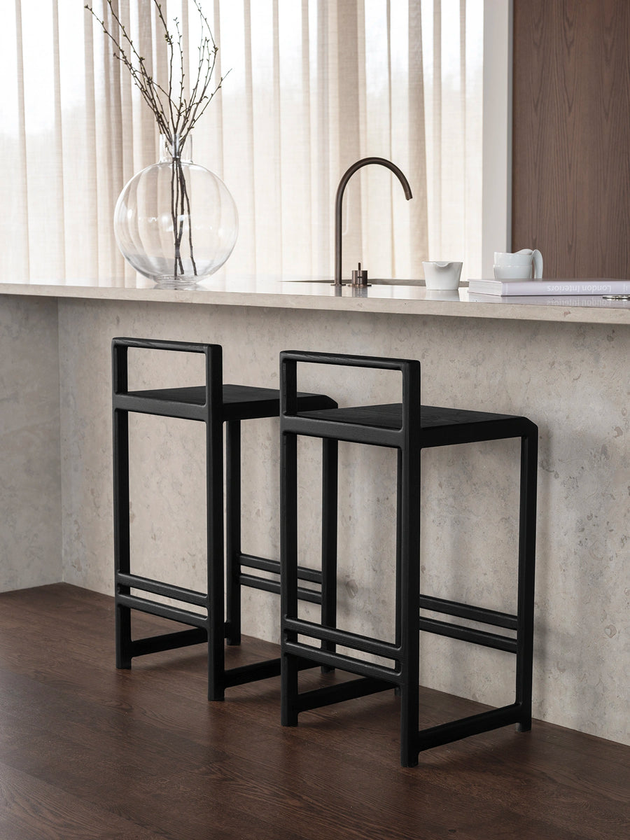 Oak Bar Stool Ebba in black oak frame positioned by a modern kitchen island with natural light.