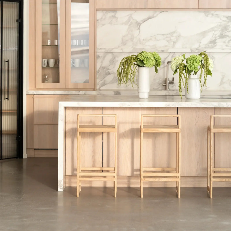 Oak Bar Stool Ebba in a modern kitchen with light wood cabinetry and marble countertops.