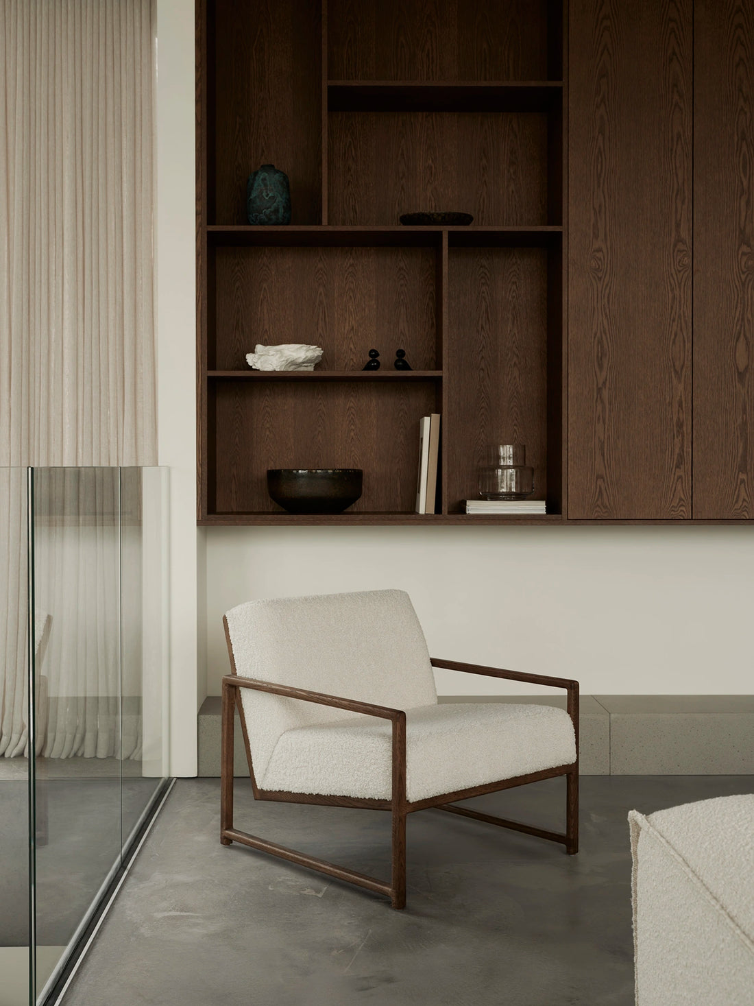 Einar lounge chair in dark oak with bouclé upholstery inside Pine Edge Villa featuring warm wood cabinetry, minimalist Scandinavian architecture, and soft natural light.