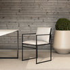 Modern Elsy outdoor chair in black with cushion, set in contemporary outdoor space with green plant.