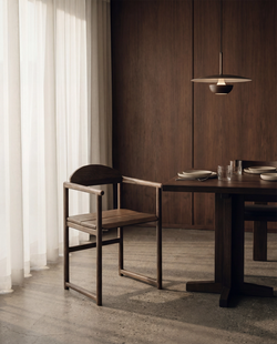 Erik dining chair in dark oak with armrests, solid wood Scandinavian design styled at a minimalist dining table with warm wood interior.