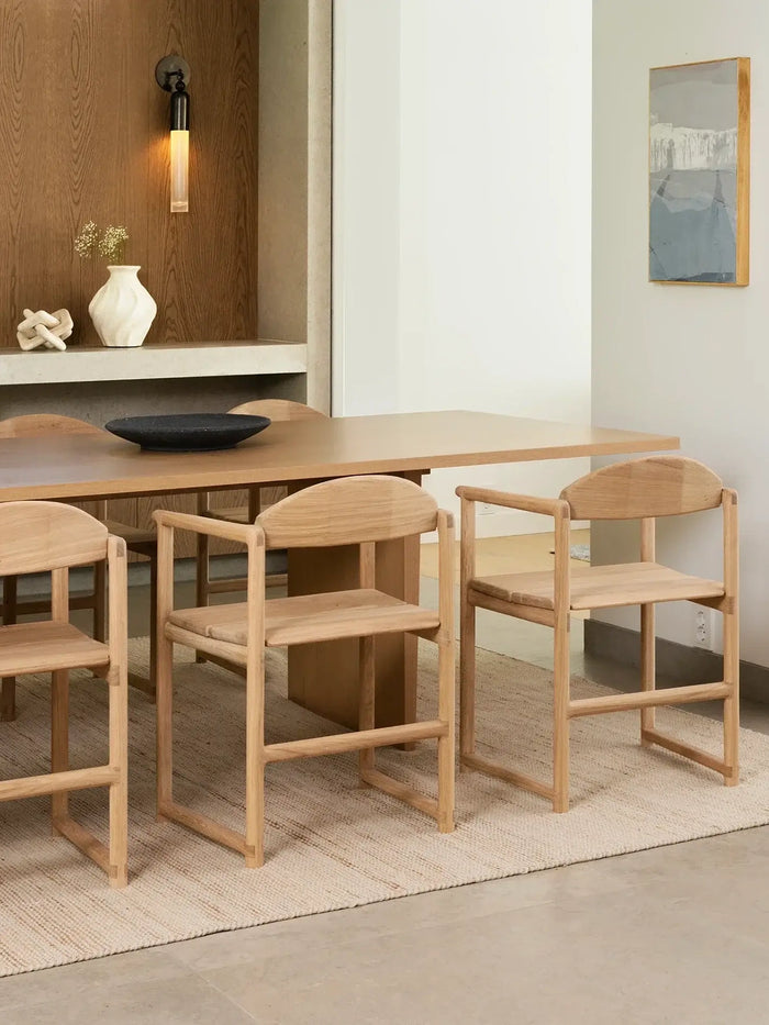 Erik oak dining chairs around a modern wooden dining table in a warm minimalist interior with Scandinavian-inspired decor and natural textures.
