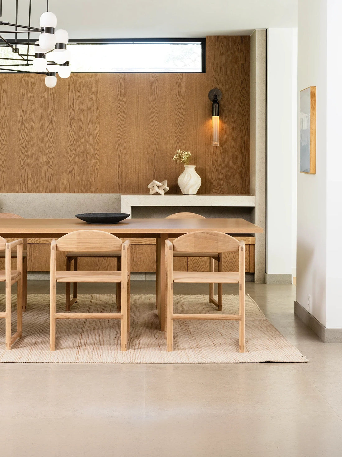 Erik dining chairs in solid oak inside a hyper-modern Scandinavian villa in Saltsjöbaden, Stockholm, Sweden with warm wood paneling and minimalist Danish design details.