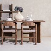 Dining chair Erik with greige bouclé cushion next to a dining table and floral centerpiece, modern interior design.