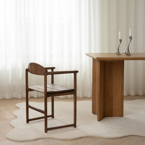 Erik dining chair in dark oak next to a wooden table, set in a bright room with sheer curtains.
