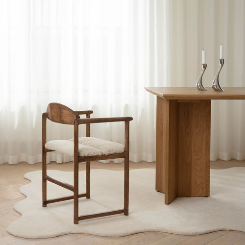 Erik dining chair in dark oak with ivory bouclé fabric, complementing a modern dining table in a bright, airy setting.