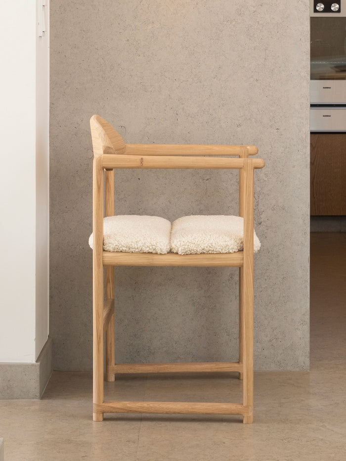 Oak Dining Chair Erik, solid oak frame with a screw-mounted ivory bouclé cushion, at a dining table
