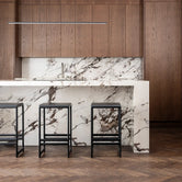 Modern kitchen featuring black oak bar stools and a stylish marble countertop with wooden cabinets.