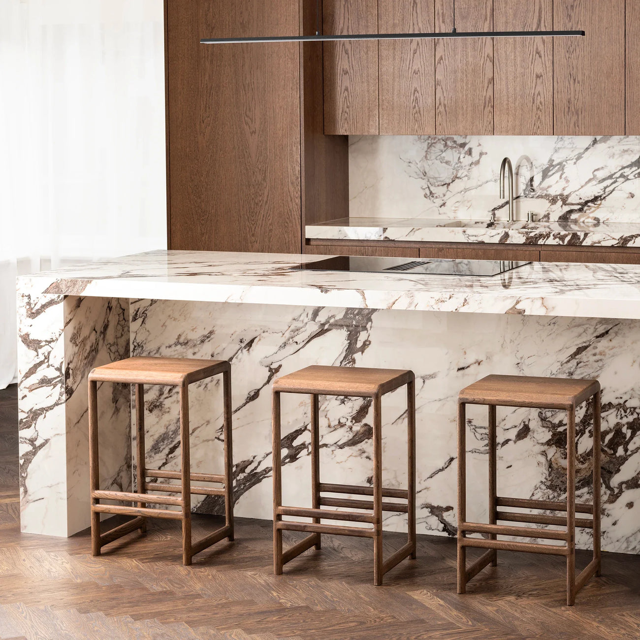 Sculpted dark oak Eva bar stools with low-back design at a modern kitchen counter.