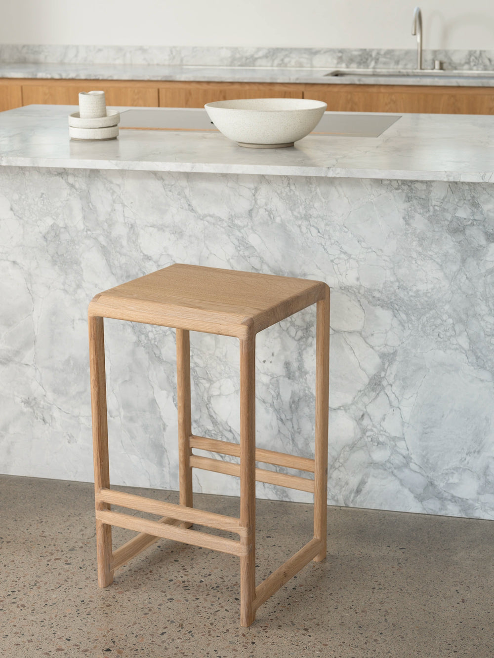 Oak Bar Stool Eva positioned in a modern kitchen with a marble countertop.