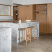 Natural oak Eva bar stools in a modern kitchen with marble countertops, showcasing minimalist design and comfort.