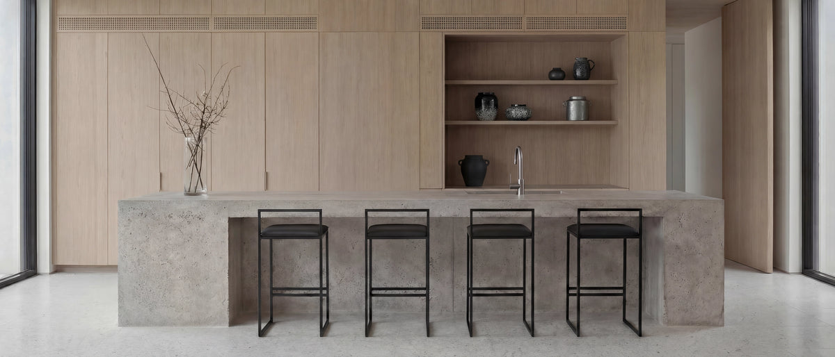 Four Freja bar stools with black frames at a concrete kitchen island