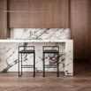 Freja bar stools in black leather against a marble kitchen island backdrop, showcasing minimalistic design and style.
