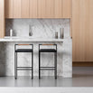Freja bar stools in black leather with sleek black frames in modern kitchen setting against marble backdrop.
