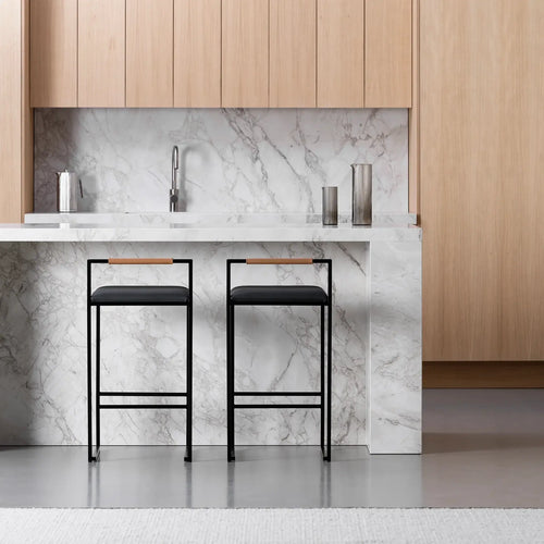 Freja bar stools in black leather with sleek black frames in modern kitchen setting against marble backdrop.
