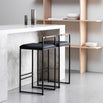 Freja bar stools in black leather with a sleek design, set against a modern kitchen backdrop with marble and wood.