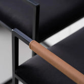 Detail of Bar Stool Freja with black frame, brown leather armrest, and black velvet cushion.