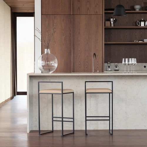 Freja bar stools with black steel frame and latte leather seats in modern kitchen setting.