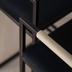 Close-up of Freja bar stool armrest featuring black frame and latte leather grip for modern interiors.