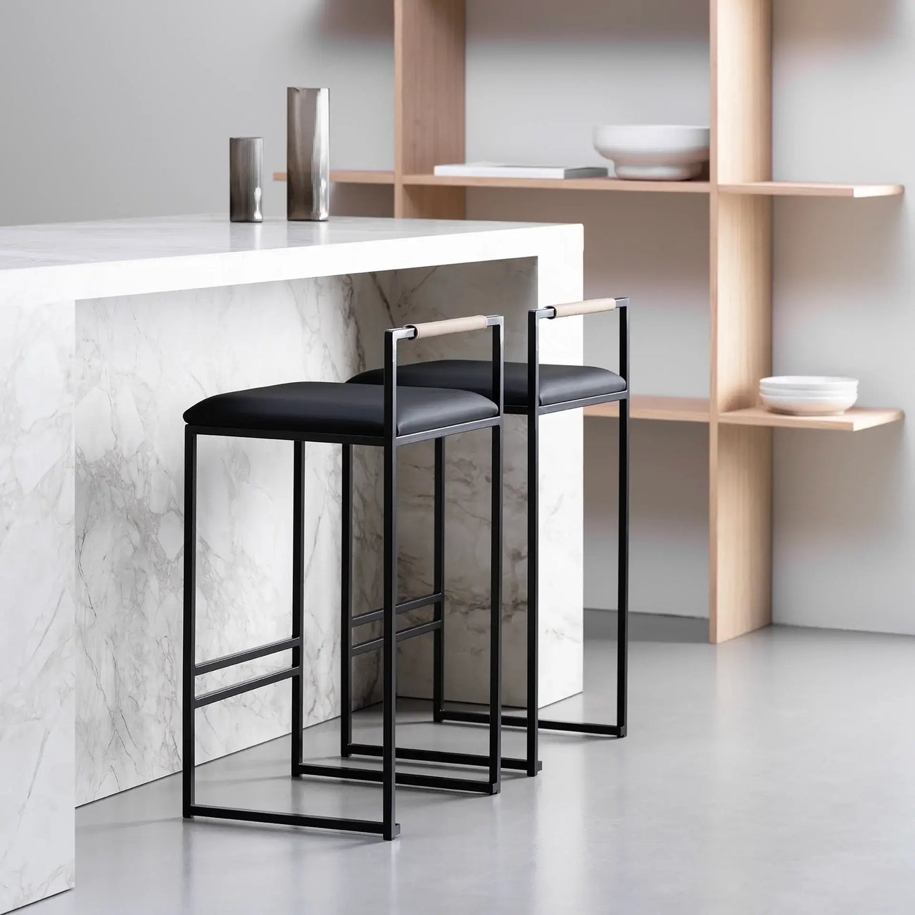 Freja bar stool in black leather with minimalist black frame, showcased in modern kitchen setting.