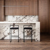 Freja bar stools in black velvet by a sleek marble and wooden kitchen island, showcasing timeless design.