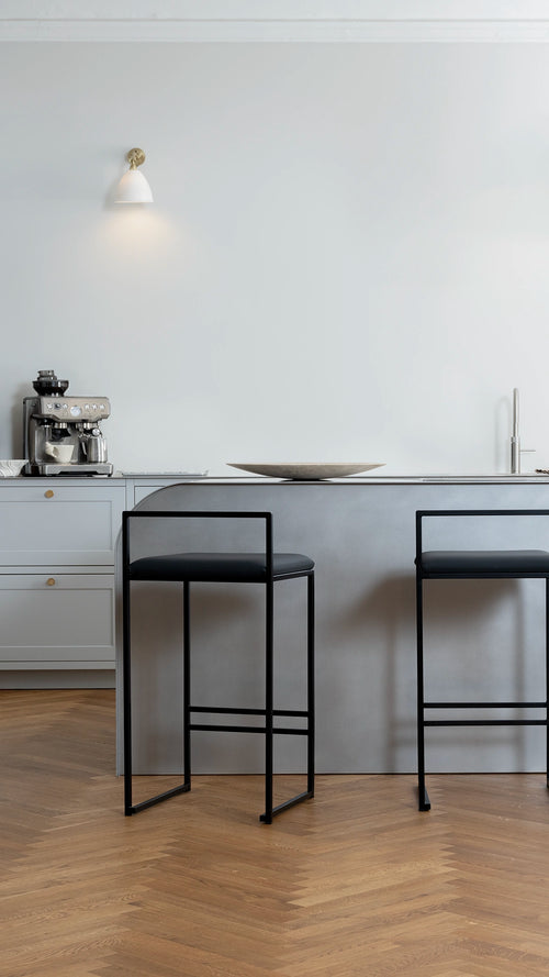 Bar Stool Freja with a black cushion on a black steel frame in an interior setting