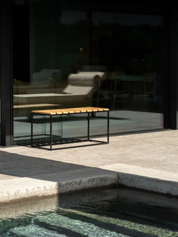 Garden Bench Hedvig in teak and stainless steel beside a pool