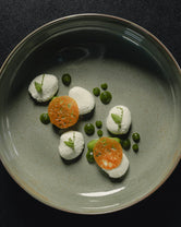 Fine dining dish at Hotel Milla Montis in South Tyrol, artfully plated with white elements, green sauces, delicate herbs and crisp garnishes on a ceramic plate.