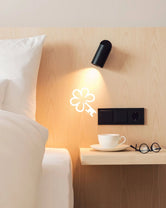 Bedside detail at Hotel Milla Montis in South Tyrol, featuring pale wood panelling, white bedding and an illuminated MICHELIN Key symbol representing the hotel’s One MICHELIN Key distinction.